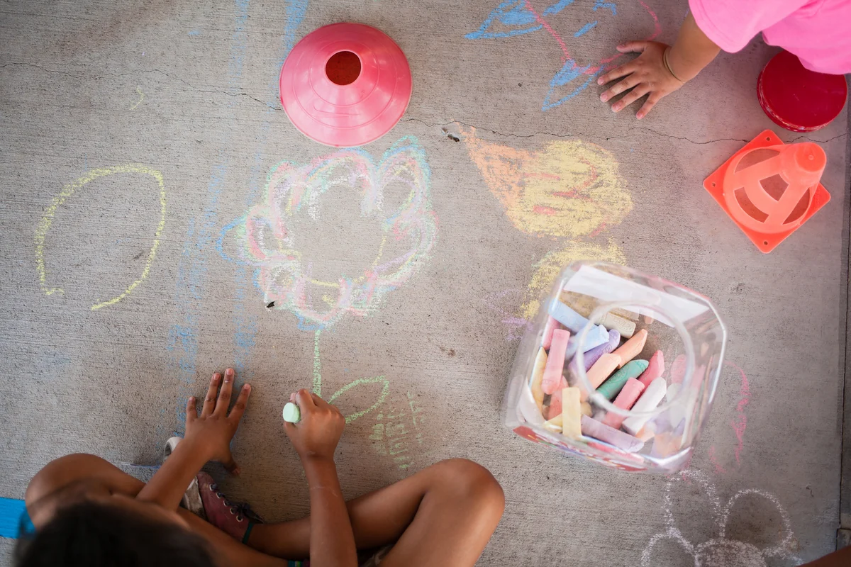 West Side Helping Hand students drawing with sidewalk chalk